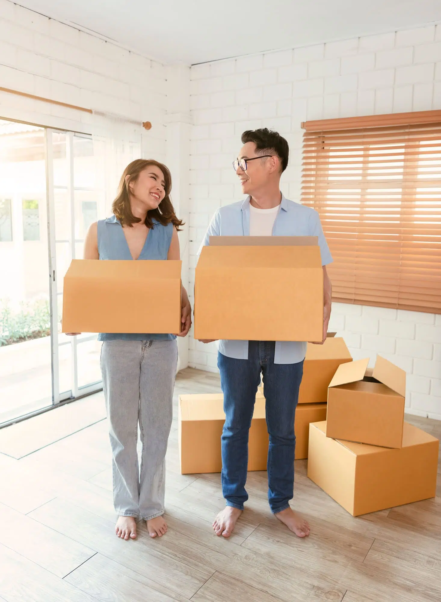 Happy Asian couple holding cardboard box go into new home. Relocation concept