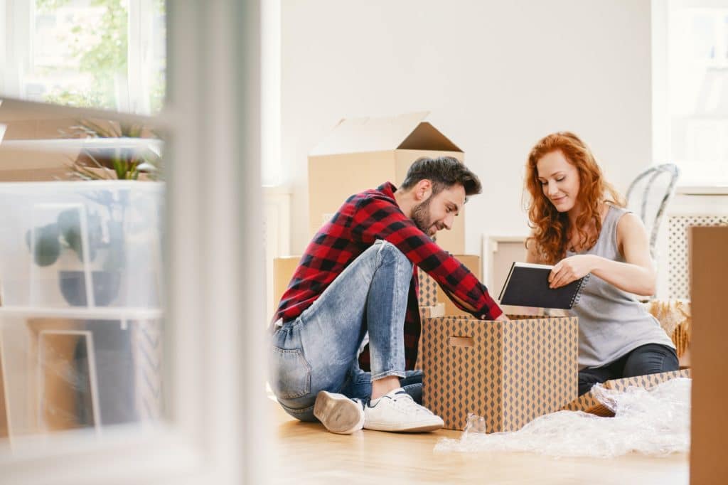 Man and woman unpacking stuff after relocation to new home